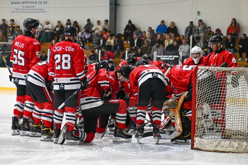 Red Devils players huddle beside the net before faceoff.